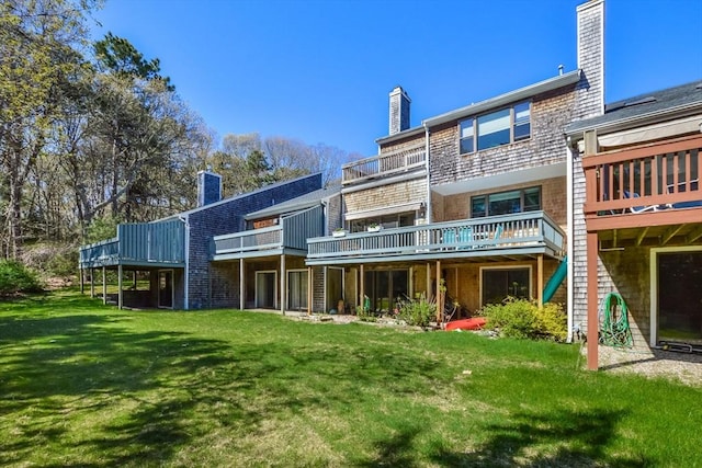 rear view of house featuring a lawn, a chimney, and a wooden deck