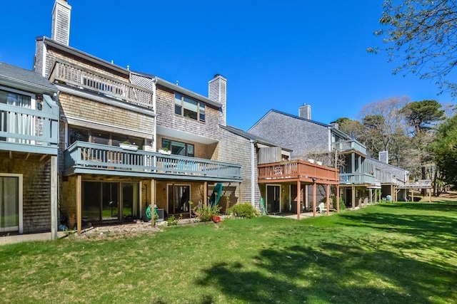 rear view of property featuring a wooden deck, a yard, and a chimney