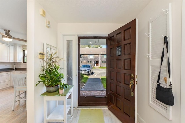 entrance foyer with ceiling fan, baseboards, and light wood finished floors