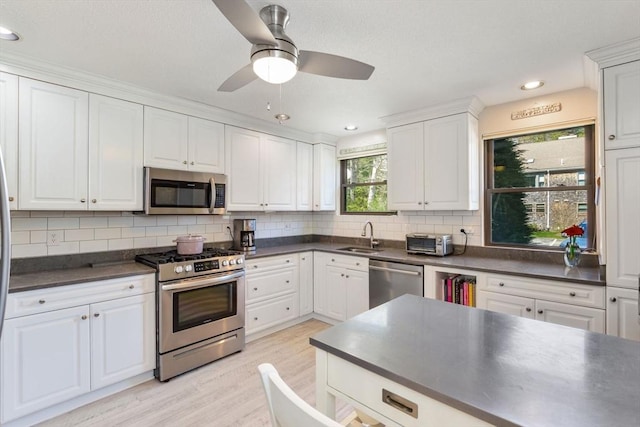 kitchen featuring a sink, dark countertops, stainless steel appliances, and light wood-style flooring