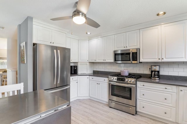 kitchen featuring dark countertops, ceiling fan, white cabinetry, appliances with stainless steel finishes, and backsplash