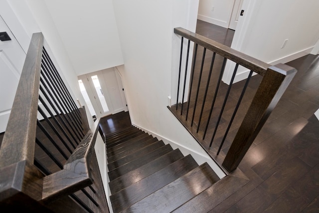 stairway with a towering ceiling and wood-type flooring