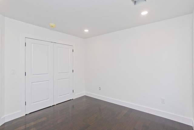 unfurnished bedroom featuring dark hardwood / wood-style flooring and a closet