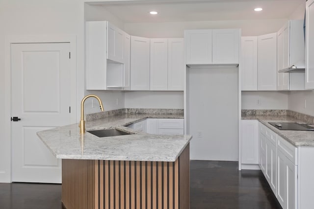 kitchen with sink, black electric stovetop, white cabinets, and light stone counters