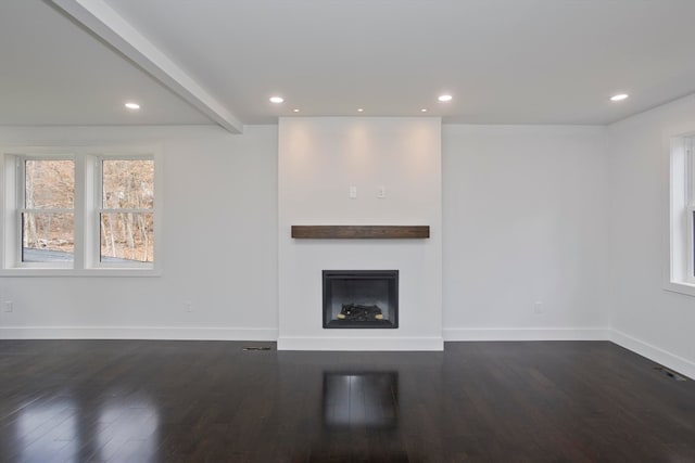 unfurnished living room featuring dark wood-type flooring and beam ceiling