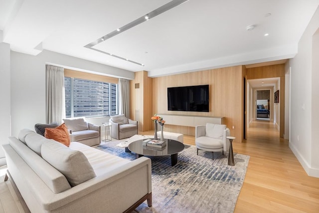 living room with wood walls, light wood-type flooring, and baseboards