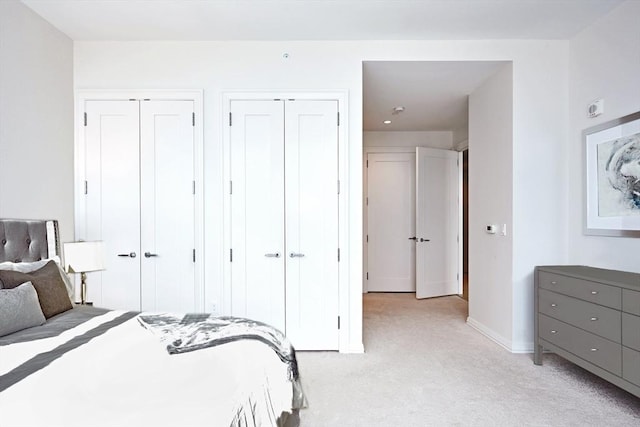 bedroom with light carpet and two closets