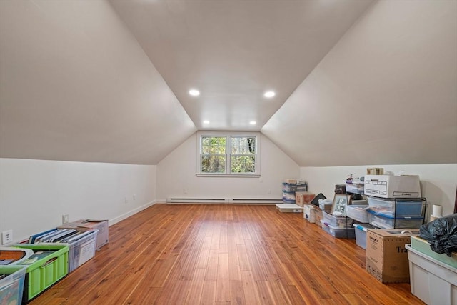 additional living space featuring a baseboard radiator, light hardwood / wood-style floors, and vaulted ceiling