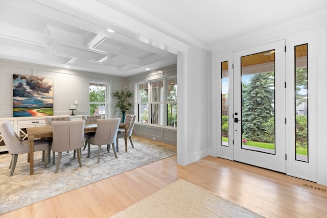 dining area with a wealth of natural light, light hardwood / wood-style flooring, coffered ceiling, and ornamental molding