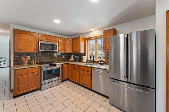 kitchen featuring sink, light tile patterned floors, stainless steel appliances, tasteful backsplash, and light stone countertops