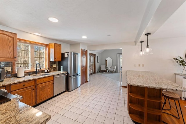 kitchen with light tile patterned flooring, sink, decorative backsplash, hanging light fixtures, and stainless steel appliances