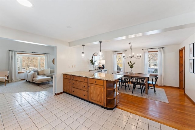 kitchen with a chandelier, light tile patterned floors, kitchen peninsula, pendant lighting, and light stone countertops