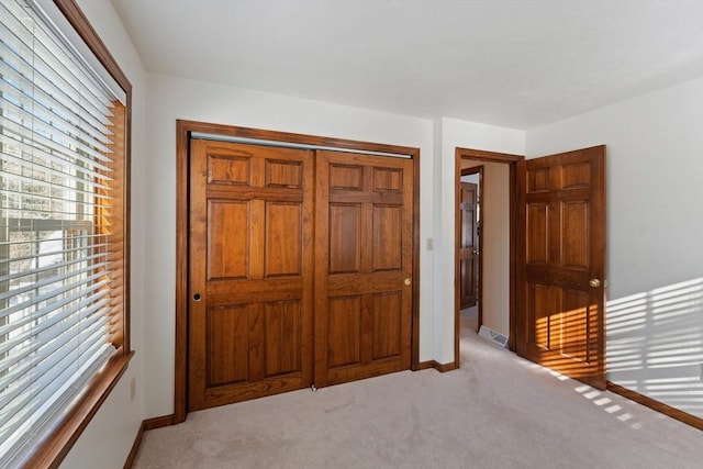 unfurnished bedroom with light carpet and a closet