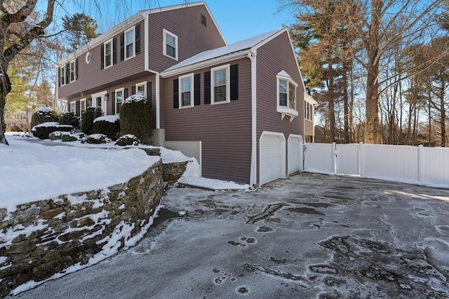 snow covered property with a garage