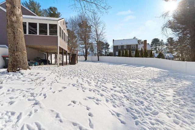 yard layered in snow with a sunroom