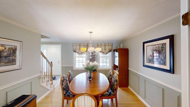 dining area with an inviting chandelier, ornamental molding, and light hardwood / wood-style flooring