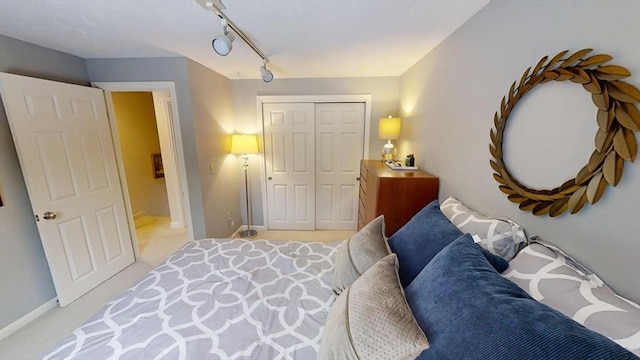 bedroom with track lighting, light colored carpet, and a closet