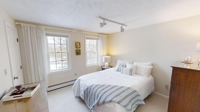 carpeted bedroom with a baseboard radiator and track lighting