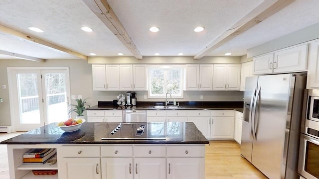 kitchen featuring white cabinetry, appliances with stainless steel finishes, beam ceiling, and a kitchen island