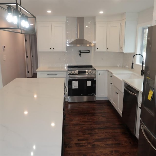 kitchen with stainless steel appliances, white cabinetry, wall chimney exhaust hood, and sink