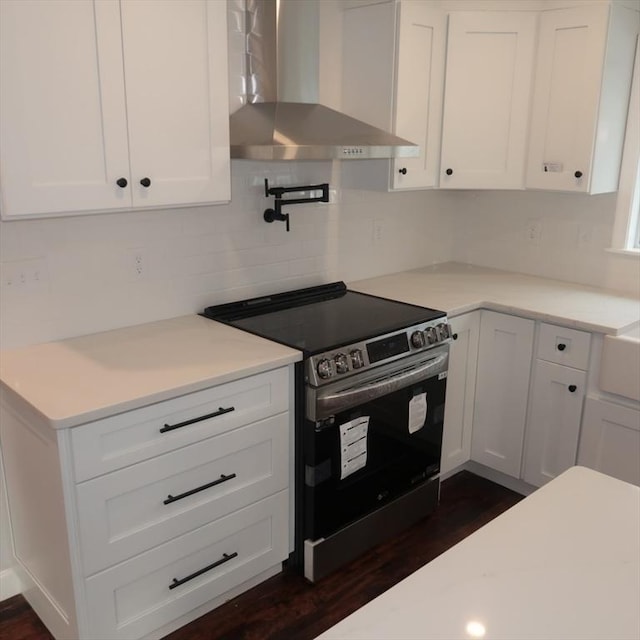 kitchen featuring white cabinetry, stainless steel electric range oven, wall chimney range hood, tasteful backsplash, and dark hardwood / wood-style flooring