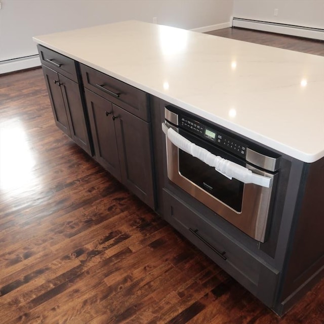 kitchen with baseboard heating, dark brown cabinetry, dark hardwood / wood-style flooring, and oven