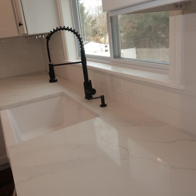 room details with light stone countertops, white cabinetry, and sink