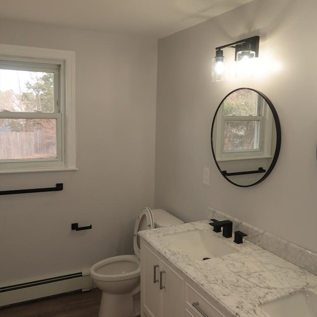 bathroom with toilet, vanity, a baseboard radiator, and hardwood / wood-style flooring