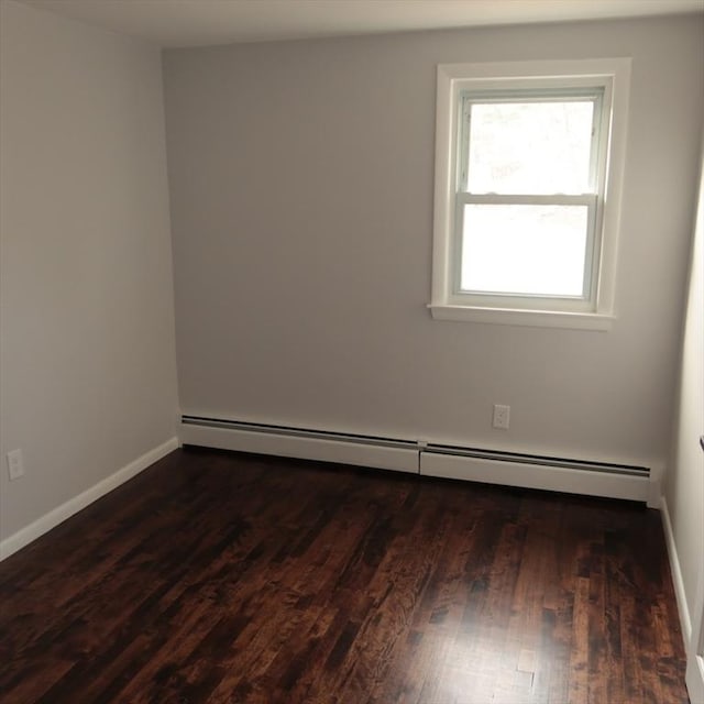 empty room with dark hardwood / wood-style flooring and a baseboard heating unit