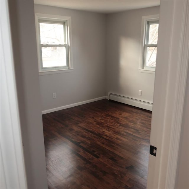 empty room featuring dark hardwood / wood-style flooring and baseboard heating