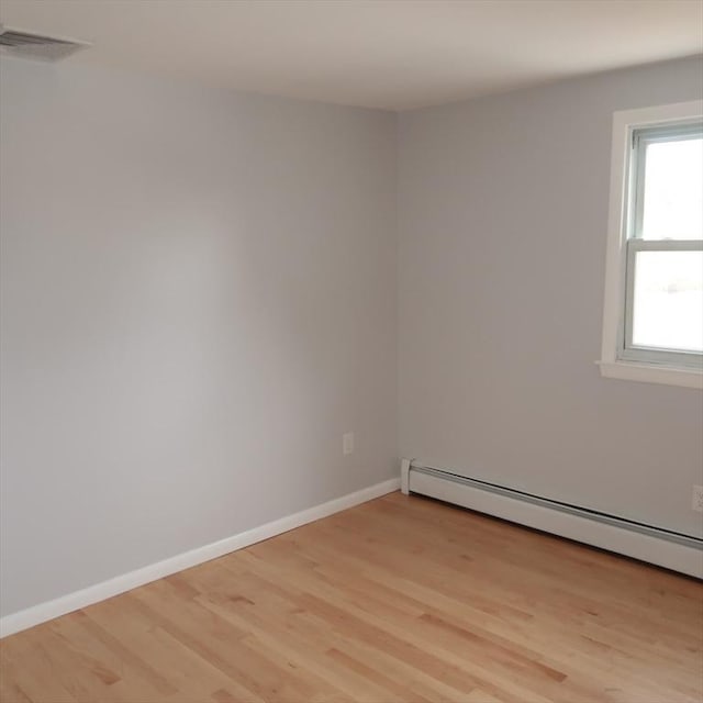 unfurnished room with light hardwood / wood-style floors and a baseboard heating unit