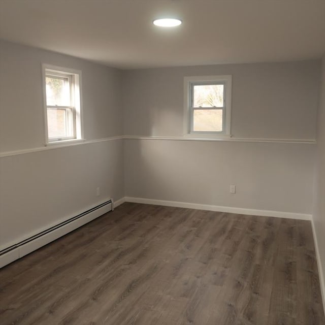 unfurnished room with dark hardwood / wood-style floors and a baseboard heating unit