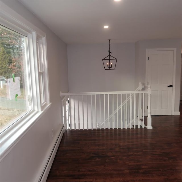 stairs with hardwood / wood-style floors, a baseboard radiator, and an inviting chandelier