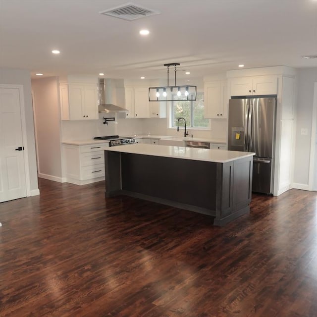 kitchen featuring appliances with stainless steel finishes, dark hardwood / wood-style flooring, a kitchen island, and wall chimney exhaust hood