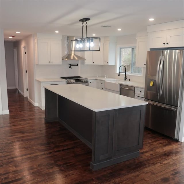 kitchen with a center island, wall chimney exhaust hood, stainless steel appliances, dark hardwood / wood-style flooring, and white cabinets