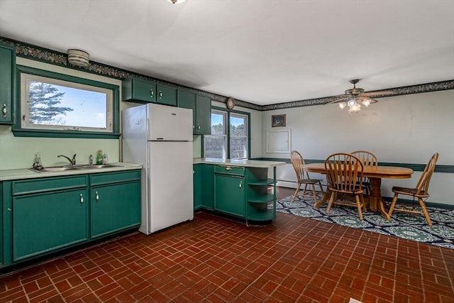 kitchen featuring green cabinets, brick floor, and freestanding refrigerator