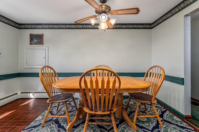 dining area with brick floor, baseboards, and ceiling fan