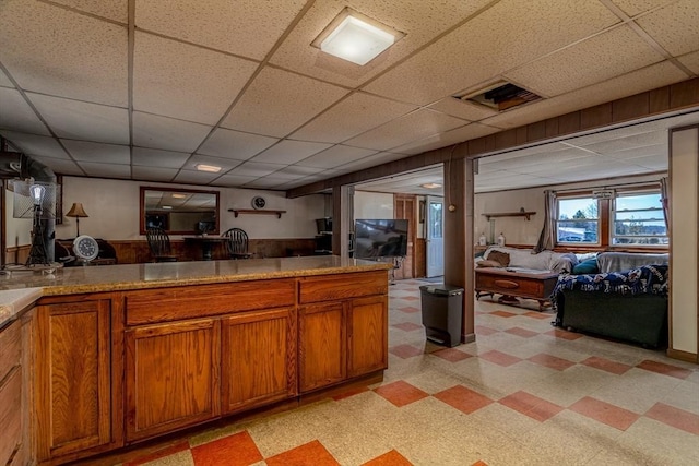 kitchen featuring brown cabinets, visible vents, a drop ceiling, and light floors