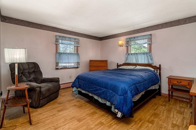 bedroom featuring baseboards, light wood-style flooring, and baseboard heating