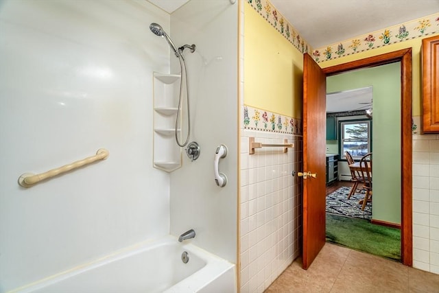 bathroom with tile walls, washtub / shower combination, and tile patterned flooring