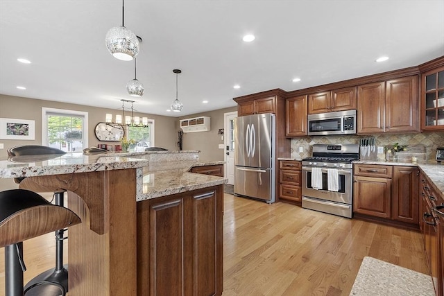 4 Elizabeth Rd, Hudson, MA 01749 - kitchen with stainless steel appliances, a breakfast bar, a wall unit AC, light wood-style floors, and backsplash