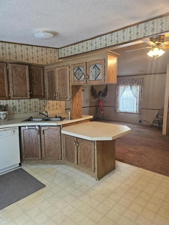 kitchen featuring sink, a textured ceiling, white dishwasher, and kitchen peninsula