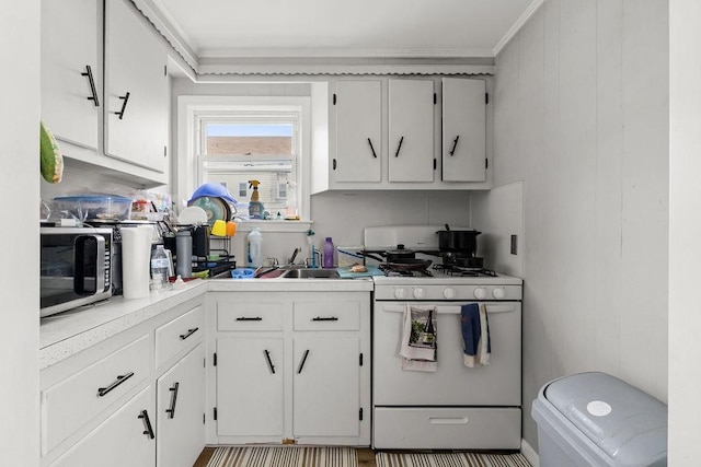 135 Snell, Fall River, MA 02721 - kitchen featuring white range with gas stovetop, stainless steel microwave, ornamental molding, light countertops, and white cabinets