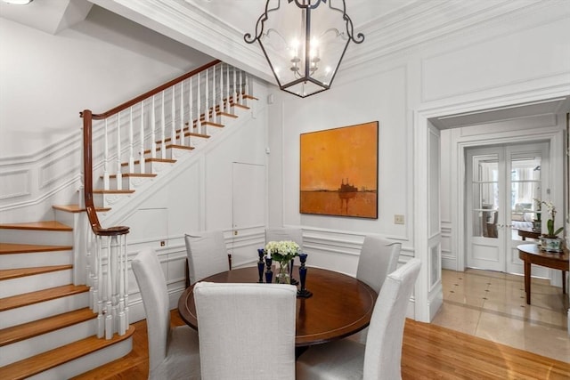 dining space with an inviting chandelier, a decorative wall, and stairway