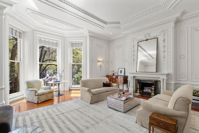 interior space featuring wood finished floors, a fireplace with flush hearth, a decorative wall, and ornamental molding