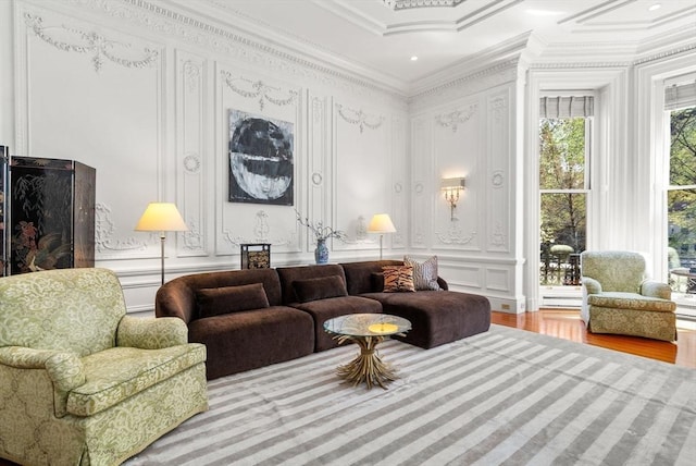 sitting room with ornamental molding, a decorative wall, and wood finished floors