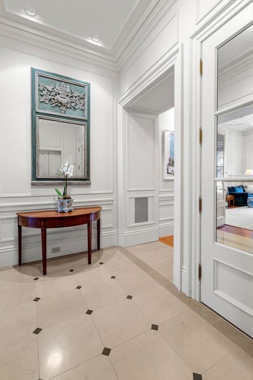 corridor with ornamental molding, a decorative wall, and tile patterned floors