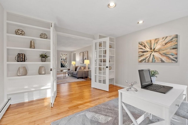 office area with built in shelves, hardwood / wood-style floors, a baseboard radiator, and french doors