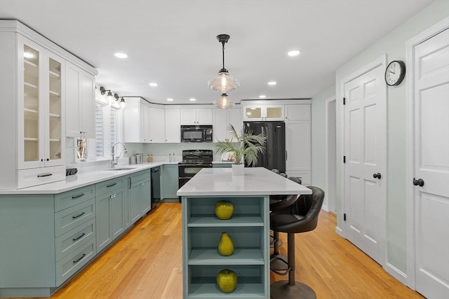 kitchen with white cabinetry, sink, black appliances, and light wood-type flooring