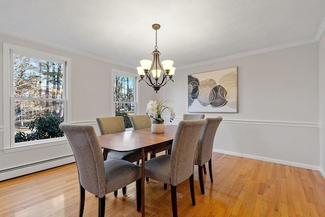 dining space with crown molding, light hardwood / wood-style flooring, a chandelier, and a baseboard heating unit